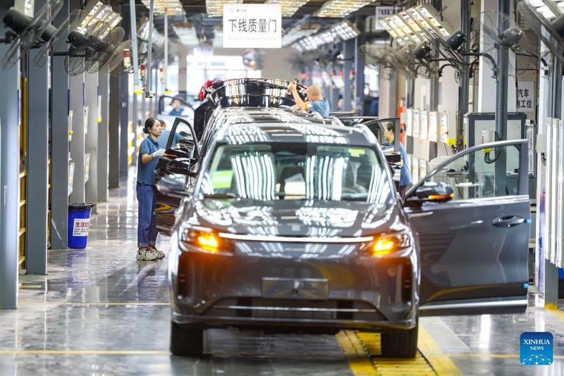 Workers inspect vehicles at a factory of carmaker Seres in southwest China's Chongqing Municipality, July 29, 2026.